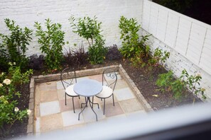 Sit and unwind in this serene outdoor seating area with a round table and two comfortable chairs.