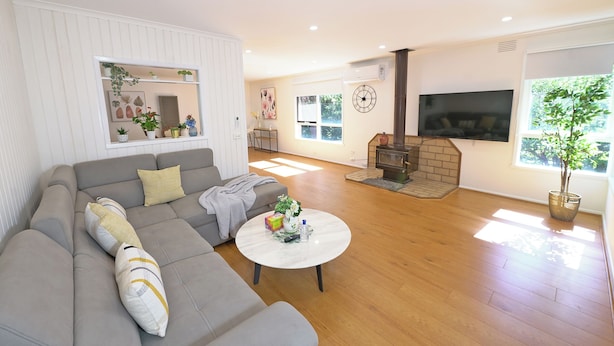A modern living room with a grey sofa, a round coffee table, and a fireplace. - Melbourne 4BRM Staycation Parkside (Hallam)