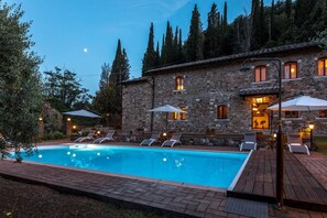Un bâtiment en pierre doté d’une piscine, d’un espace extérieur aménagé et offrant une vue sur les arbres et les collines.