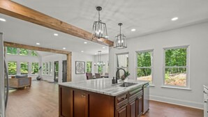A spacious kitchen with a large island, wooden beams, and large windows. - Luxury Home w/Private Dock and Pool (Gainesville)