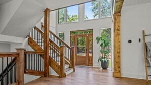 A spacious interior with a wooden staircase, large windows, and a potted plant. - Luxury Home w/Private Dock and Pool (Gainesville)
