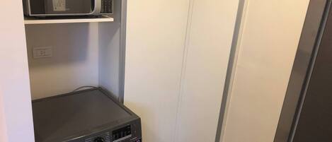 A laundry room with a washing machine, a microwave, and a refrigerator.