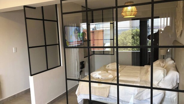 A bedroom with a bed, a television, and a window with a view of the outside. - Apartment First Flor Excellent Location (Salta)