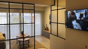 A living room with a TV, a sofa, a coffee table, and a decorative wall panel. - Apartment First Flor Excellent Location (Salta)