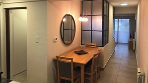 A dining area with a wooden table and chairs, a wall-mounted mirror, and a window with blinds. - Apartment First Flor Excellent Location (Salta)