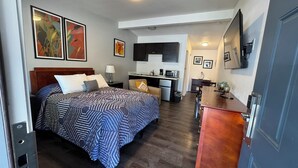 Een hotelkamer met een bed, een bureau, een kitchenette en een televisie.