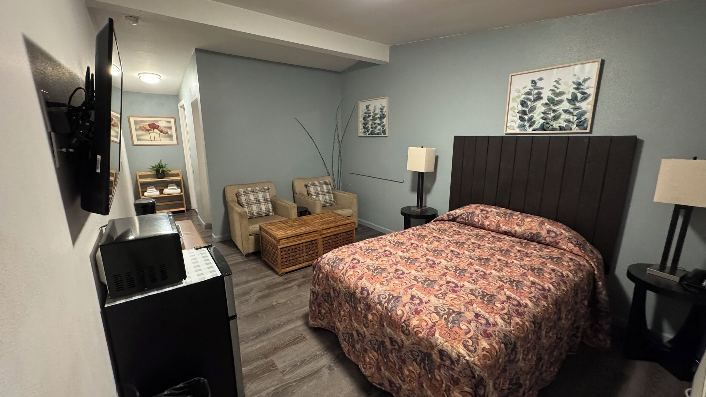 Een hotelkamer met een bed, een bureau, een stoel, een lamp en een televisie.