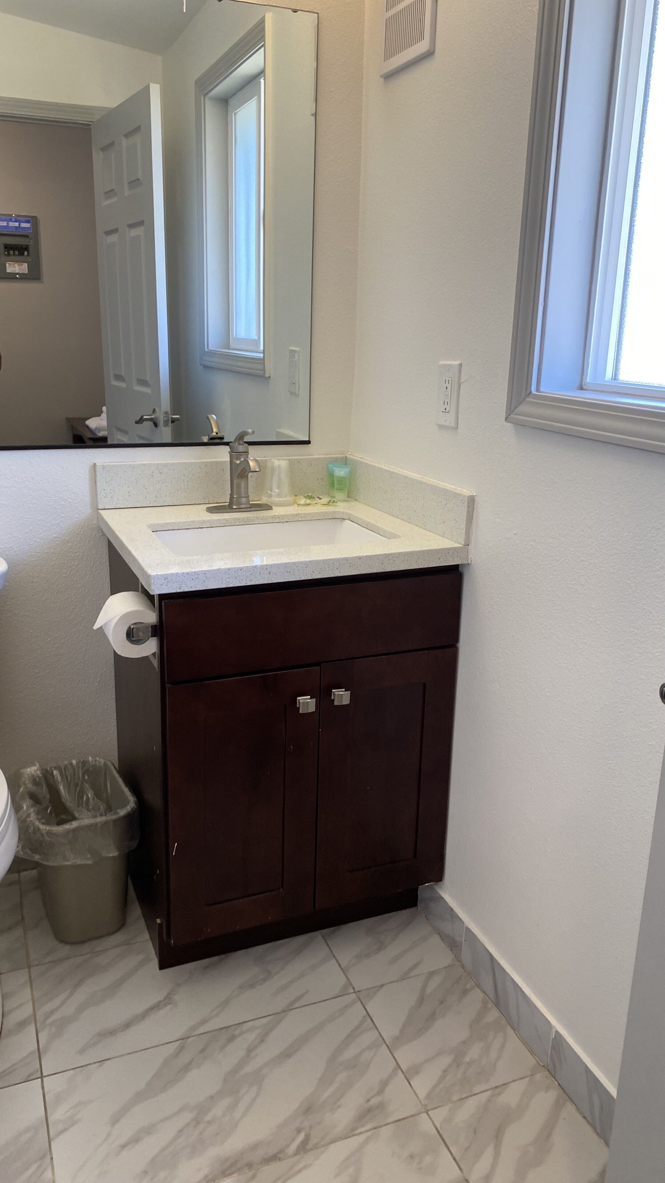A bathroom with a white sink, dark wooden vanity, and a mirror.
