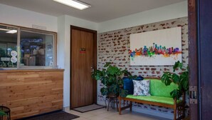 Een receptie met een houten balie, een deur en een kleurrijk stadsgezicht op de muur.