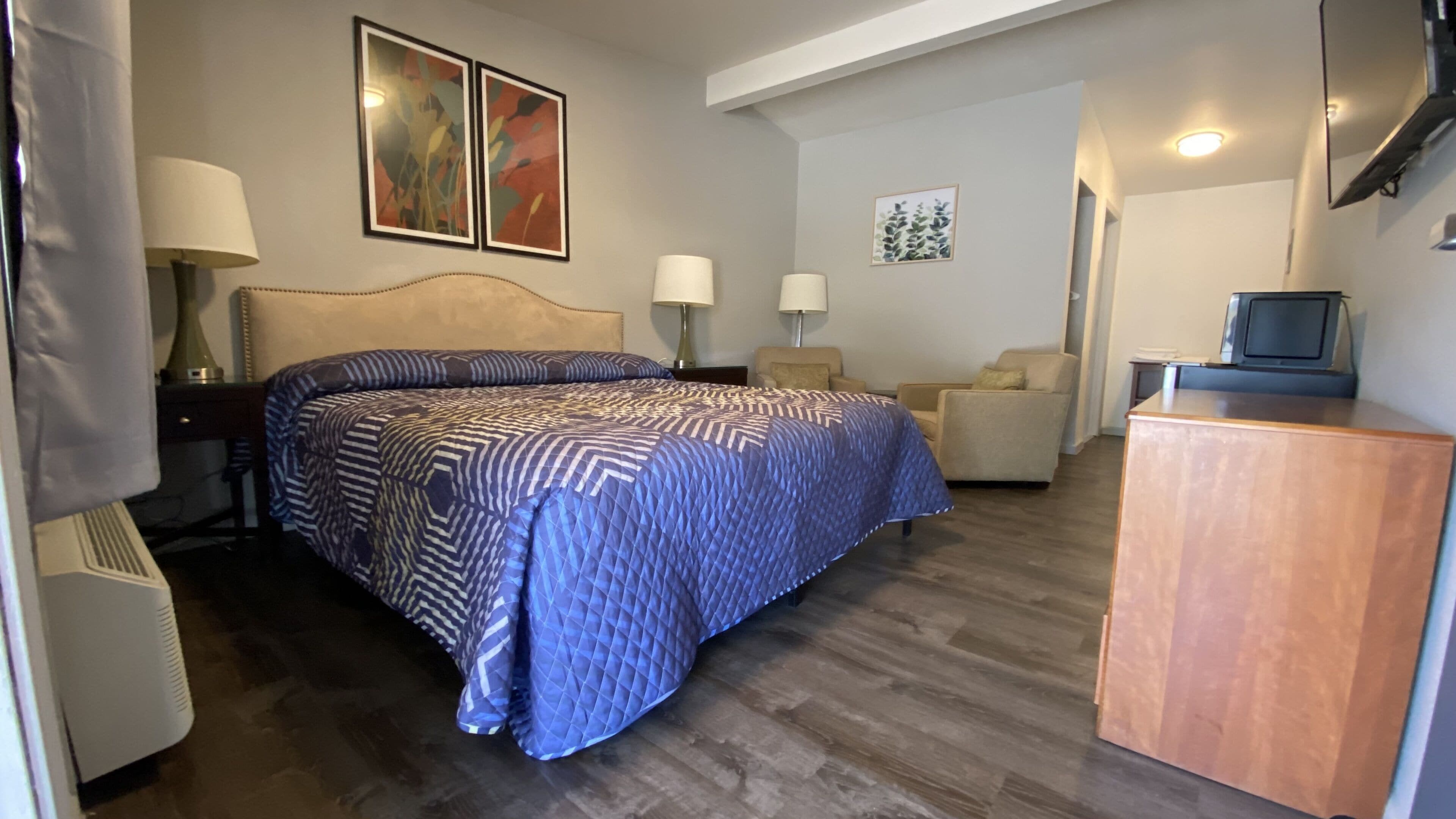 Habitación de hotel con una cama grande, un escritorio, una silla y un televisor.
