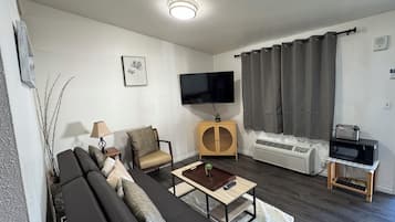 En stue med en sofa, et sofabord, et fjernsyn og et lille skab.