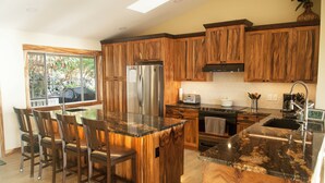 A modern kitchen with wooden cabinets, a stainless steel refrigerator, and a granite countertop. - Panoramic view of ocean.  Excellent location. Quiet neighborhood. Sleep 10 (Kailua-Kona)