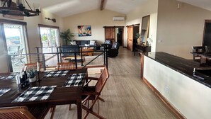 A spacious living area with a dining table, chairs, a sofa, and a large mirror. - Panoramic view of ocean.  Excellent location. Quiet neighborhood. Sleep 10 (Kailua-Kona)