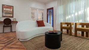 Un salon avec un canapé blanc, une table basse ronde noire et deux chaises en bois.
