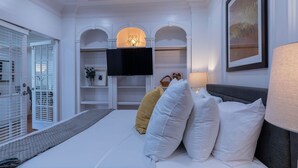 Une chambre à coucher avec un lit, un téléviseur à écran plat, une lampe et un tableau encadré au mur.
