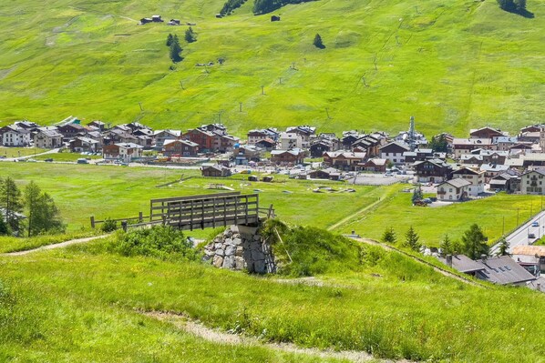 A village with traditional houses, a bridge, and a ski lift in the background.