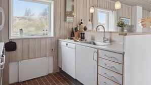 Eine moderne Küche mit Holzvertäfelung, einem großen Fenster und einem Geschirrspüler.
