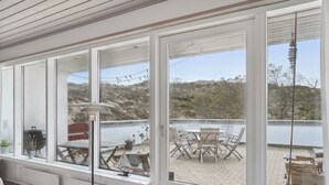 Eine überdachte Terrasse mit Blick auf einen See, einem Grill und Gartenmöbeln.