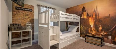 A bunk bed room with a brick wall, a television, a bookshelf, and a castle mural.