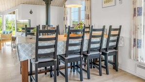 Un coin repas avec une table et des chaises en bois, une grande fenêtre avec des rideaux et un ventilateur de plafond.