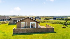 Une maison de plain-pied avec un toit en pente, un porche à l’avant et une pelouse bien entretenue.