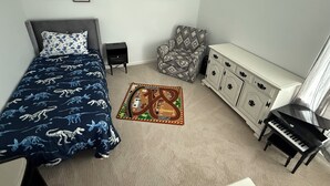 A bedroom with a bed, a small nightstand, a patterned armchair, a cabinet, and a piano. - North Lamar hideout  (Oxford)