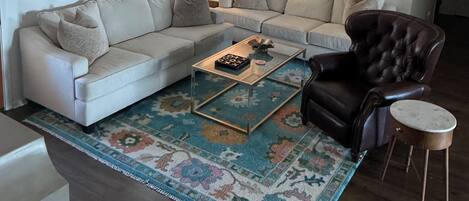 A living room with a sofa, armchair, coffee table, and a ceiling fan.
