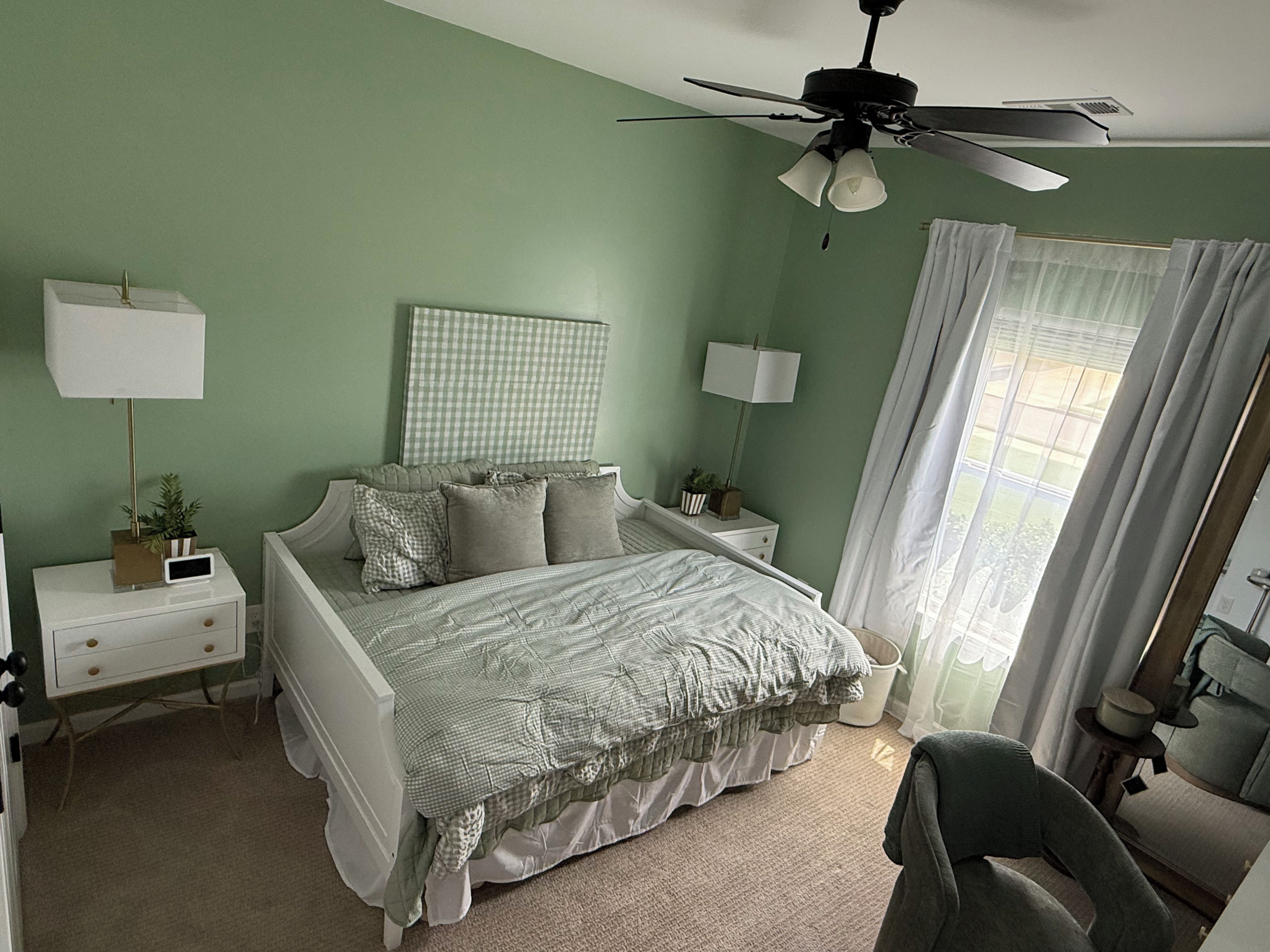A bedroom with a bed, nightstands, a ceiling fan, and a window with curtains.