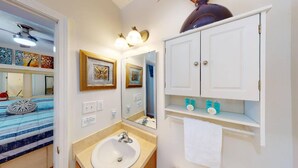 A bathroom with a white sink, mirror, and cabinet with toiletries.