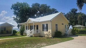 A single-story yellow house with a white porch and a small front yard.