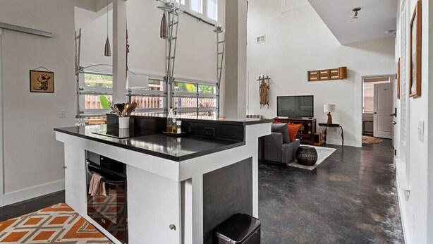 A spacious kitchen with a central island, a dining area with a sofa and TV, and a large window providing natural light. - Whitefish Lodge  Downtown Walk to Everything (St. Augustine)