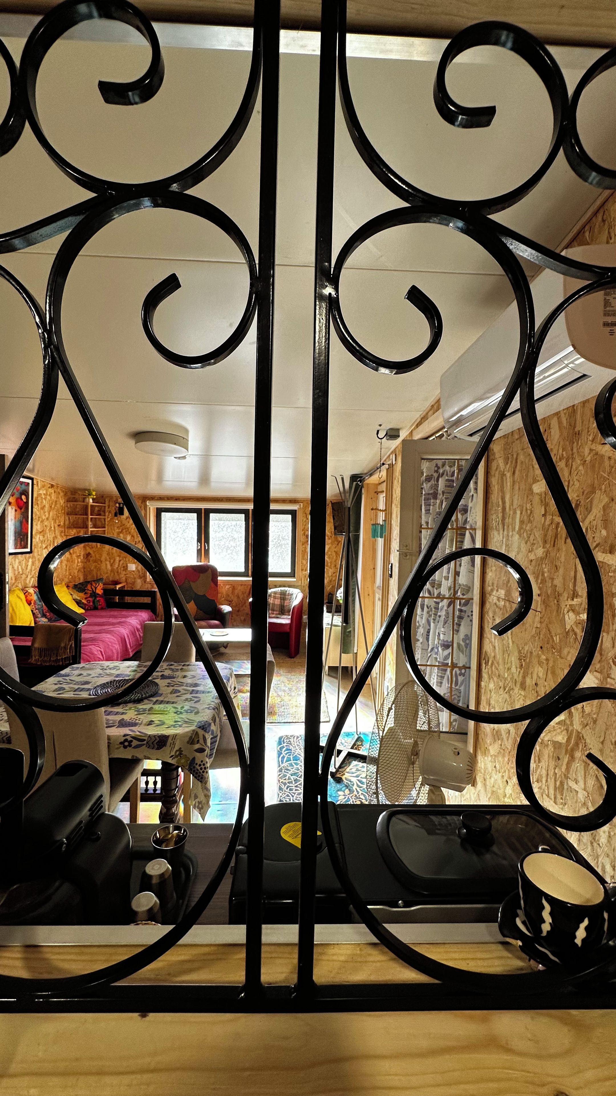 Een kamer met een bed, een stoel, een tafel en een ventilator.