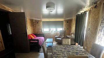 Een kleine kamer met een bed, een bureau, een stoel en een tafeltje.