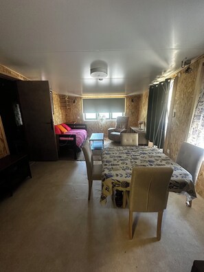 Een kleine kamer met een bed, een bureau, een stoel en een tafeltje.