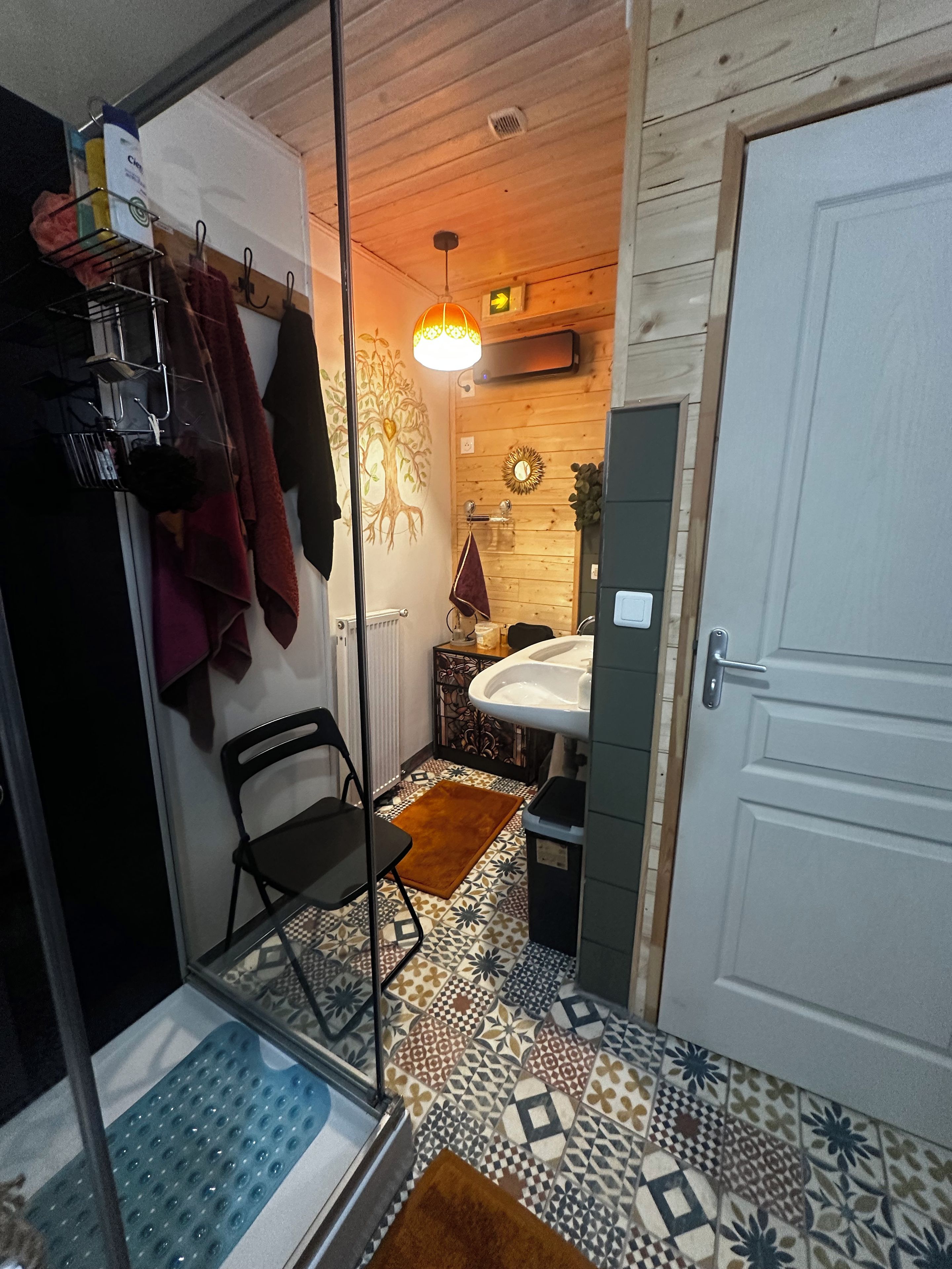 Une salle de bain avec un carrelage décoratif, un lavabo, un miroir et un porte-serviettes.