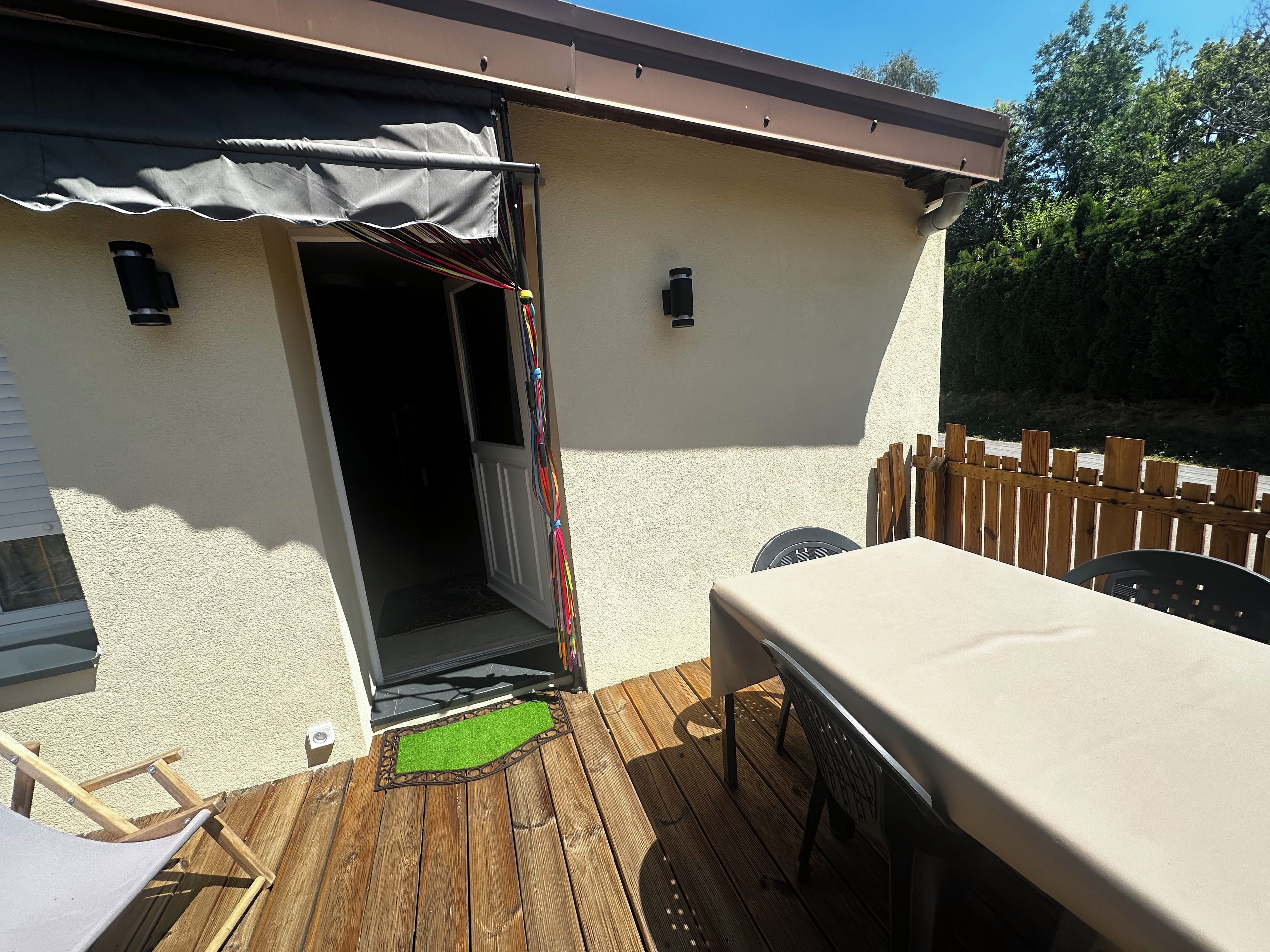 Un patio con tavolo e sedie, un pontile in legno e un ingresso coperto.