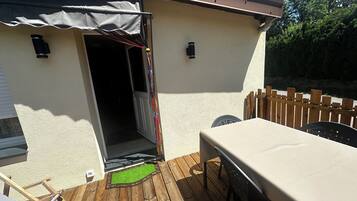 Un patio con tavolo e sedie, un pontile in legno e un ingresso coperto.