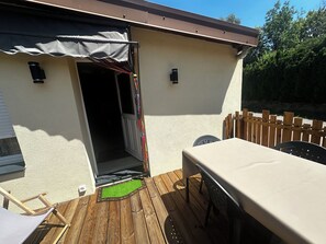 Un patio con mesa y sillas, una terraza de madera y un porche cubierto.