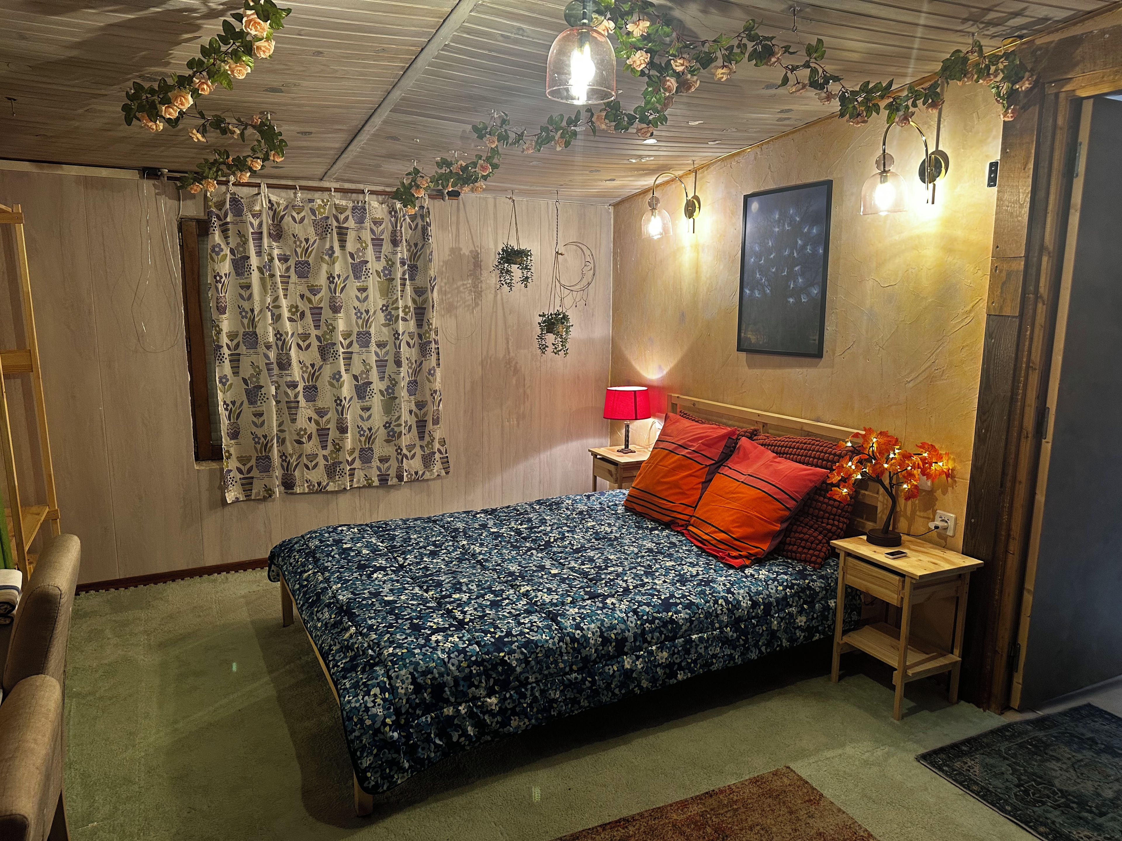 Een slaapkamer met een bed, een nachtkastje, een lamp, een wandlamp en een deur.