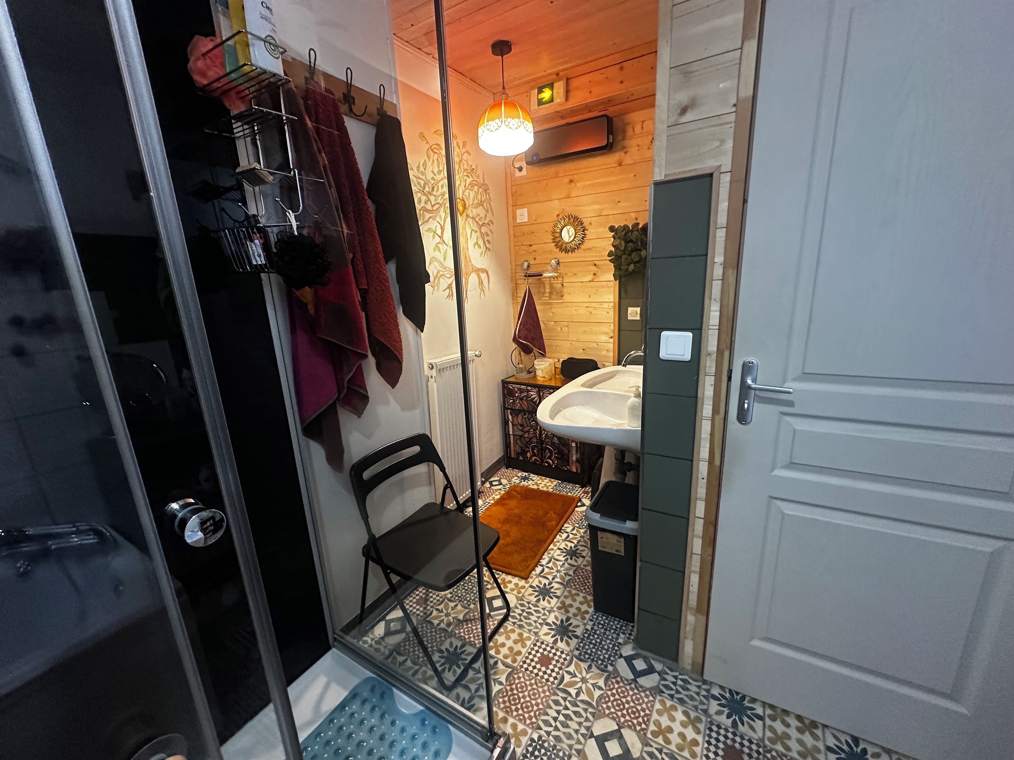 Een badkamer met een wastafel, een spiegel, een handdoekhouder en een vloer met een patroon.