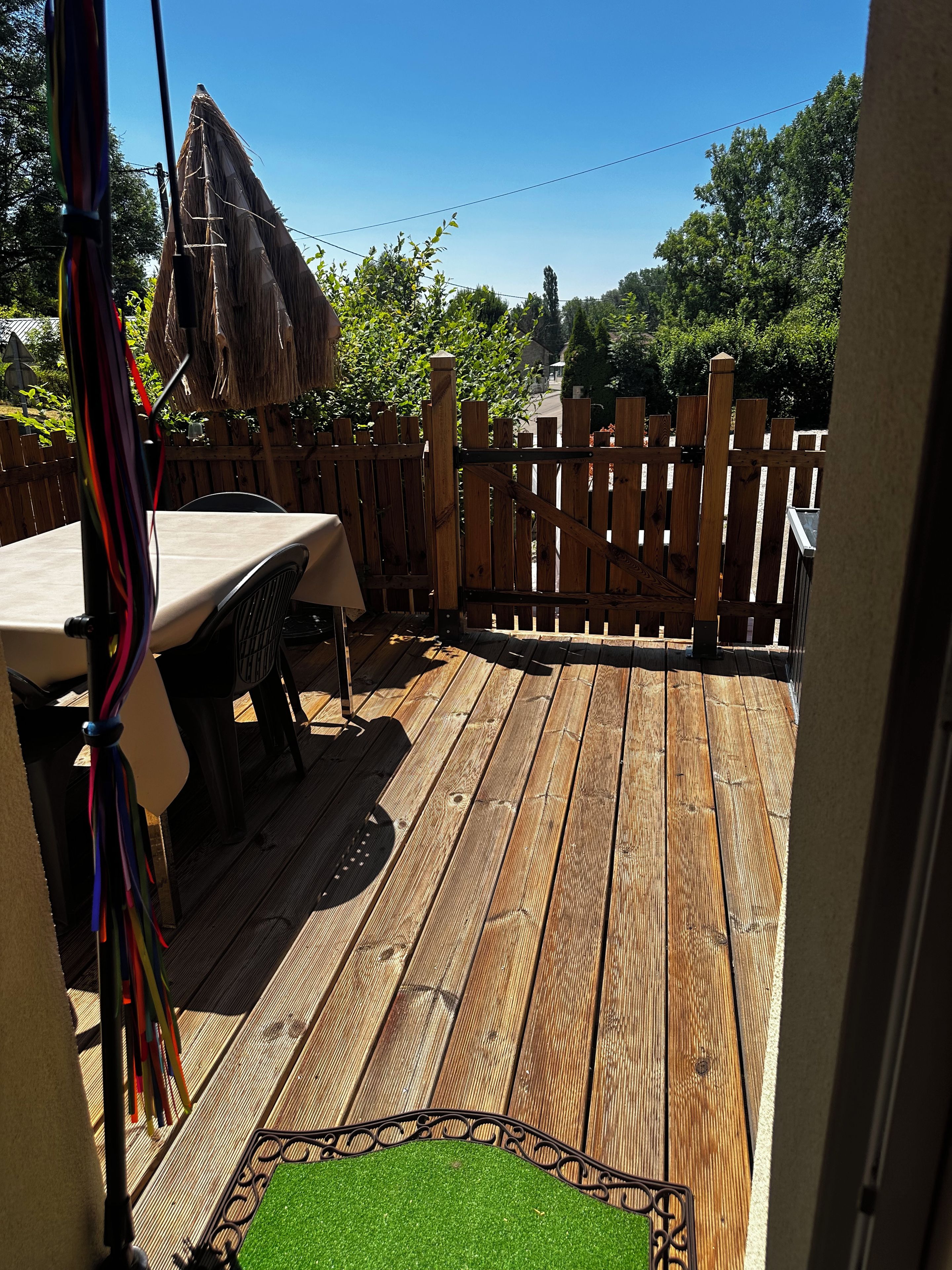 Een houten terras met een tafel en stoelen, omringd door een houten hek.