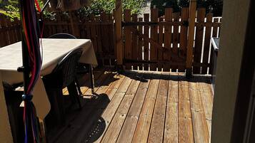 Een houten terras met een tafel en stoelen, omringd door een houten hek.