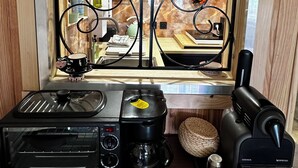Een keuken met een raam, een koffiezetapparaat, een broodrooster en een waterkoker.