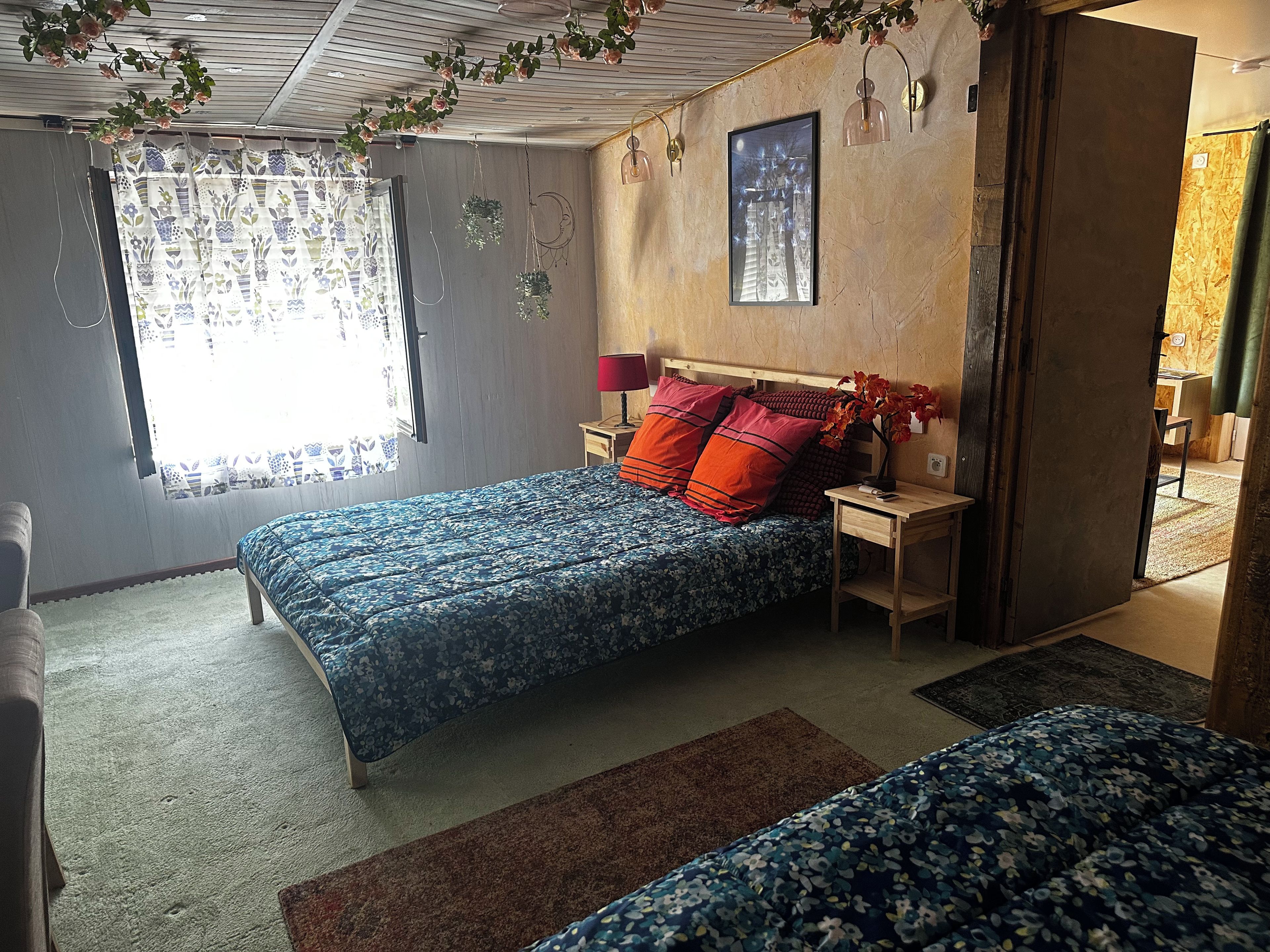 Ein Schlafzimmer mit einem Bett, Nachttischen, einer Fensterbank und einem Wandbild.