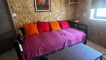 Quarto com cama, mesa de centro, pintura na parede e janela.