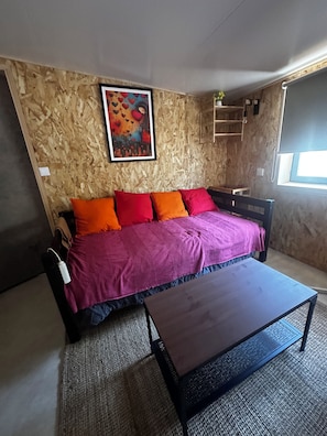 Ein Zimmer mit einem Bett, einem Couchtisch, einem Bild an der Wand und einem Fenster.
