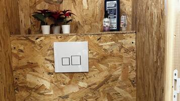 Een kleine badkamer met houten lambrisering, een toilet, een wit bedieningspaneel en een plant.