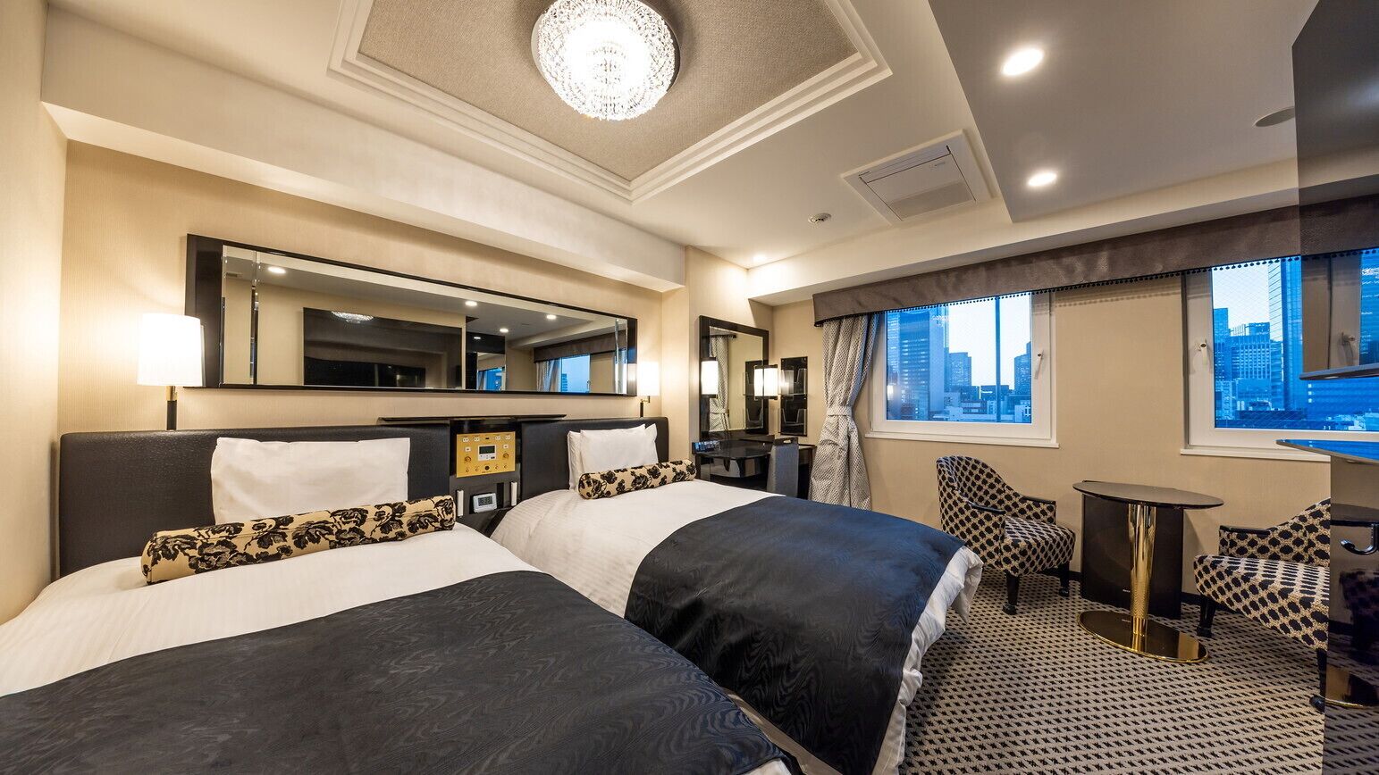 A hotel room with two beds, a large mirror, a city view, a desk, and a chair.