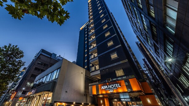 A modern hotel with a prominent sign, large windows, and a well-lit entrance.