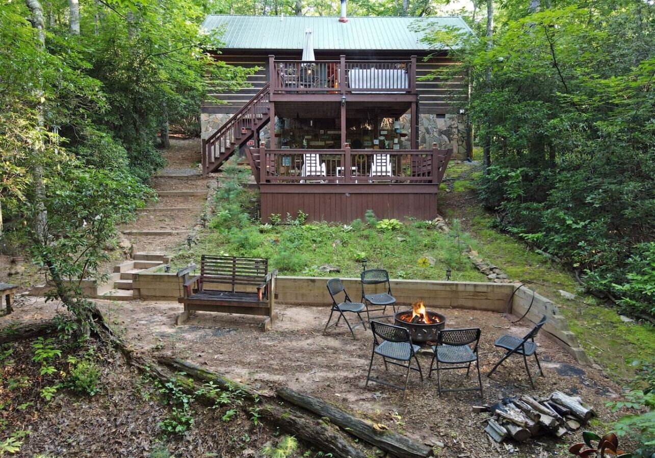 A cabin with a deck, outdoor seating, and a fire pit.